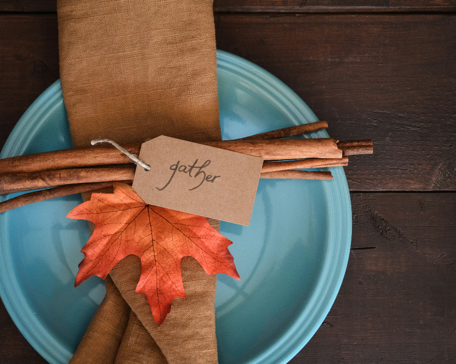 Picture of a place setting at a Thanksgiving-themed table with autumn leaves, brown napkins, and "gather" printed on tags