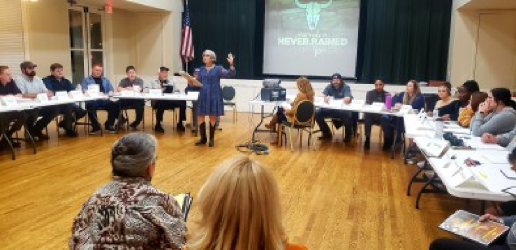 Picture of two dozen people sitting in a circle to read a script