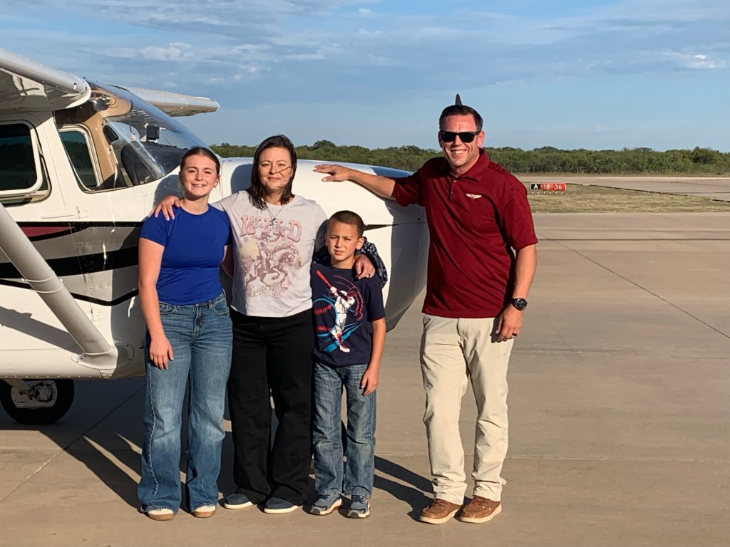 three family members and a pilot standing before a prop plane